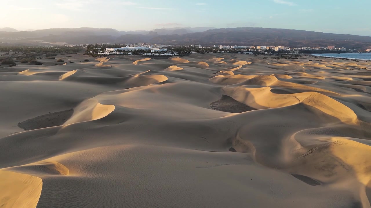 Maspalomas dunes form sweeping golden ridges near coastal resorts on Gran Canaria, aerial