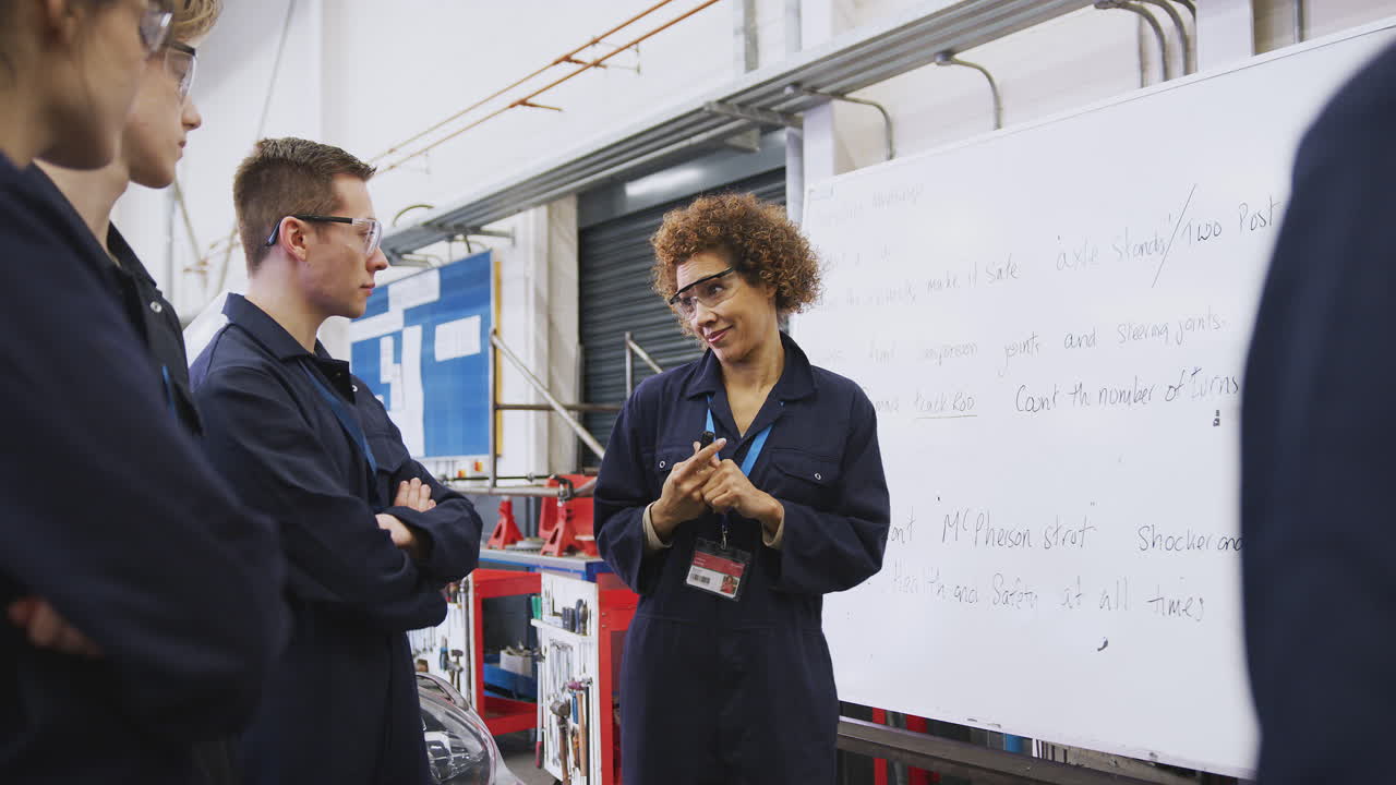tutora femenina por pizarra con estudiantes que enseñan aprendizaje de mecánica automotriz en la universidad