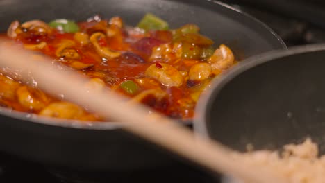 egg fried rice cooking in wok with camera panning to sweet and sour chicken dish gently simmering in hot frying pan. ready to dish and feed family traditional oriental cuisine 4k