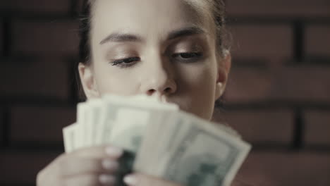 Focused-business-woman-counting-cash-money-on-brick-wall-background