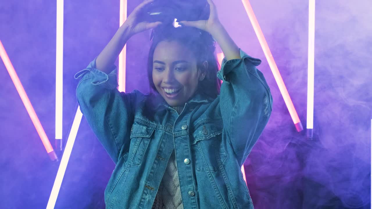 una giovane donna si mette le cuffie vr e si chiede come sia fantastico nel mondo vr. casco di realtà virtuale su sfondo di luce a colori fumo