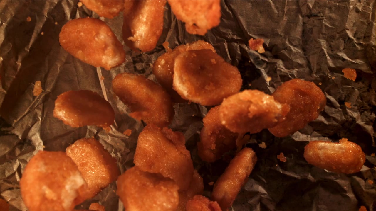 Nuggets de Frango Crocantes Caindo em Papel Amassado em Câmera Lenta