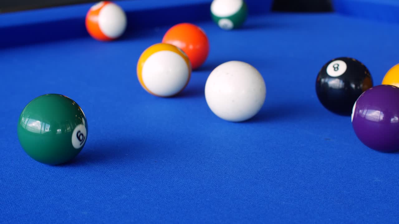 Vibrant close-up of a pool game in action, featuring a cue ball striking colorful billiard balls on a blue felt table