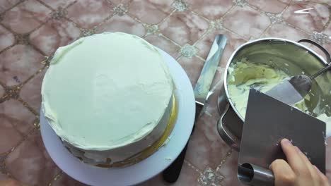 the final layer of frosting is applied to the cake