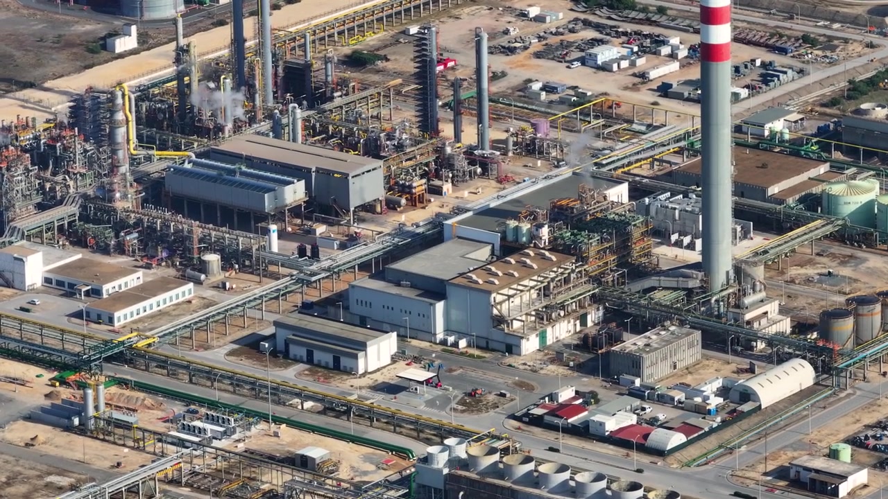 Le vedute aeree rivelano le complesse operazioni all'interno di una vivace raffineria di petrolio. I lavoratori gestiscono diligentemente la lavorazione del petrolio greggio e la produzione di carburante, vitali per il mercato energetico globale.