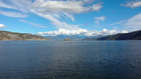 mountains lake with water reflecting white clouds on blue sky in prespa, albania