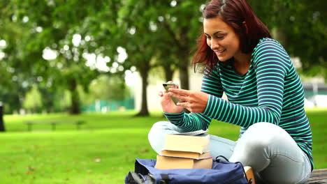 Estudiante-Bonito-Enviando-Un-Mensaje-De-Texto-En-La-Hierba