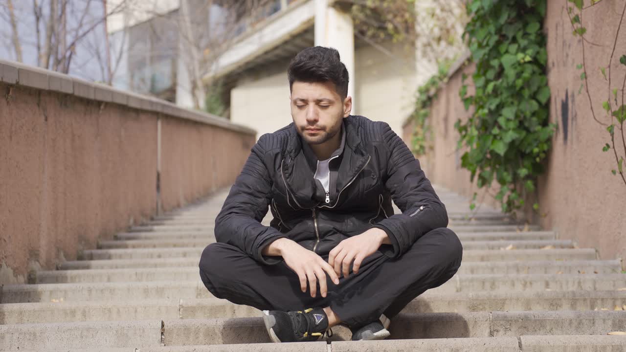 도시 밖의 계단에 앉아 있는 사려 깊고 지루한 남자.