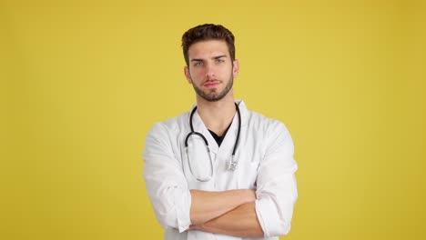 a confident male doctor with a stethoscope and lab coat stands with arms crossed against a yellow background.