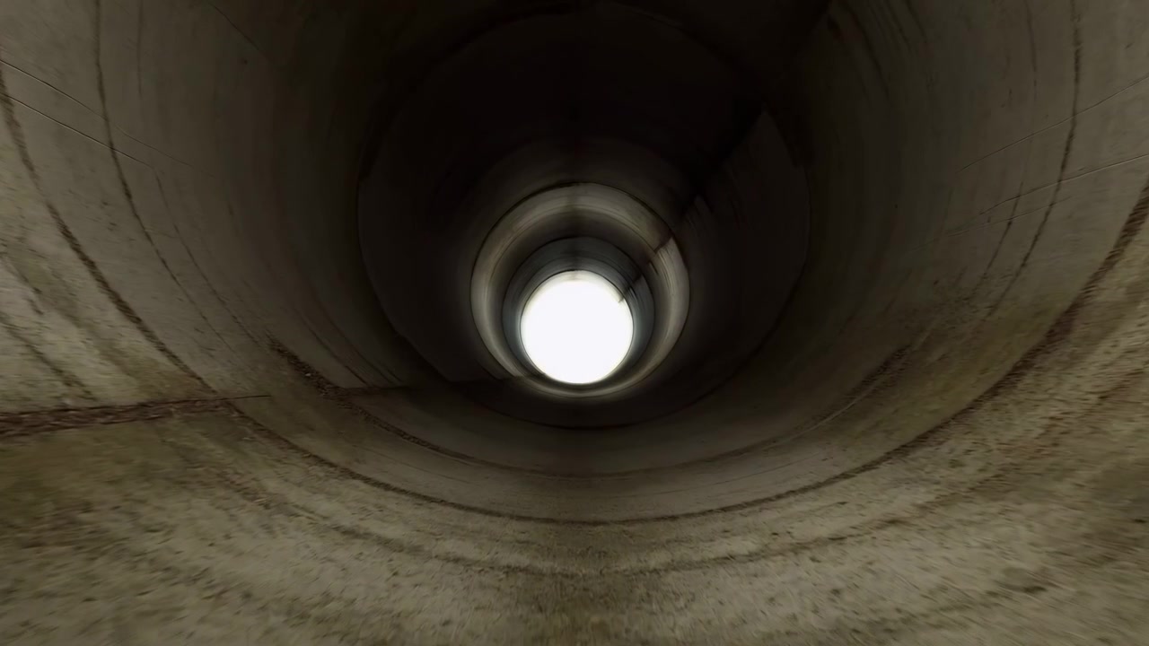 Upward view inside worn cylindrical tunnel or pipe, with bright circular opening centered amid deep shadow, gray textured walls, scratches, seams, and strong radial industrial perspective