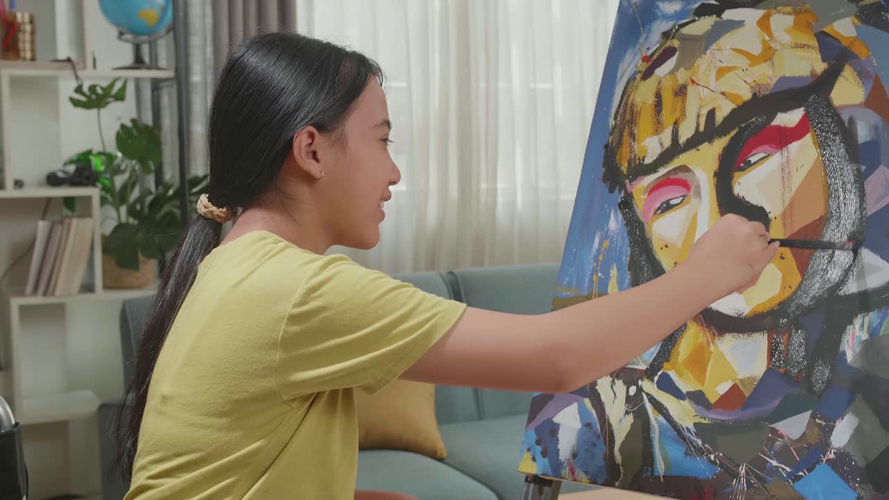 Side View Of An Asian Artist Girl In Wheelchair Holding Paintbrush Mixed Colour Thinking And Painting A Girl On The Canvas