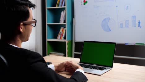 back of businessman looking at green screen laptop and talking