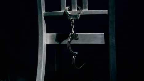 slow motion medium tracking shot of a pair of handcuffs dangling from the back of a chair