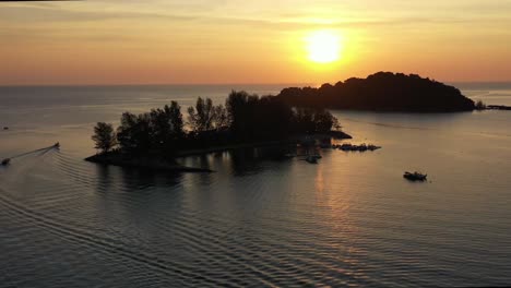 breathtaking sunset landscape, aerial flyover capturing glowing sun setting behind paradise 101 and pulau burau island, reflection on calm sea ocean, tropical paradise at langkawi, kedah, malaysia