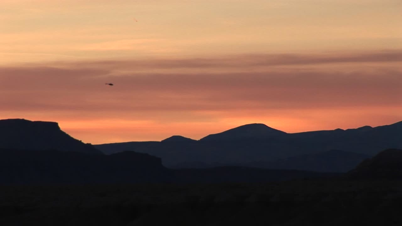 황금시간에 낮은 언덕 위로 날아가는 헬리콥터의 긴 샷