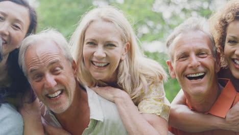 Retrato-De-Un-Grupo-Multicultural-De-Amigos-Mayores-Con-Hombres-Dando-Paseos-A-Cuestas-En-El-Campo-De-Verano