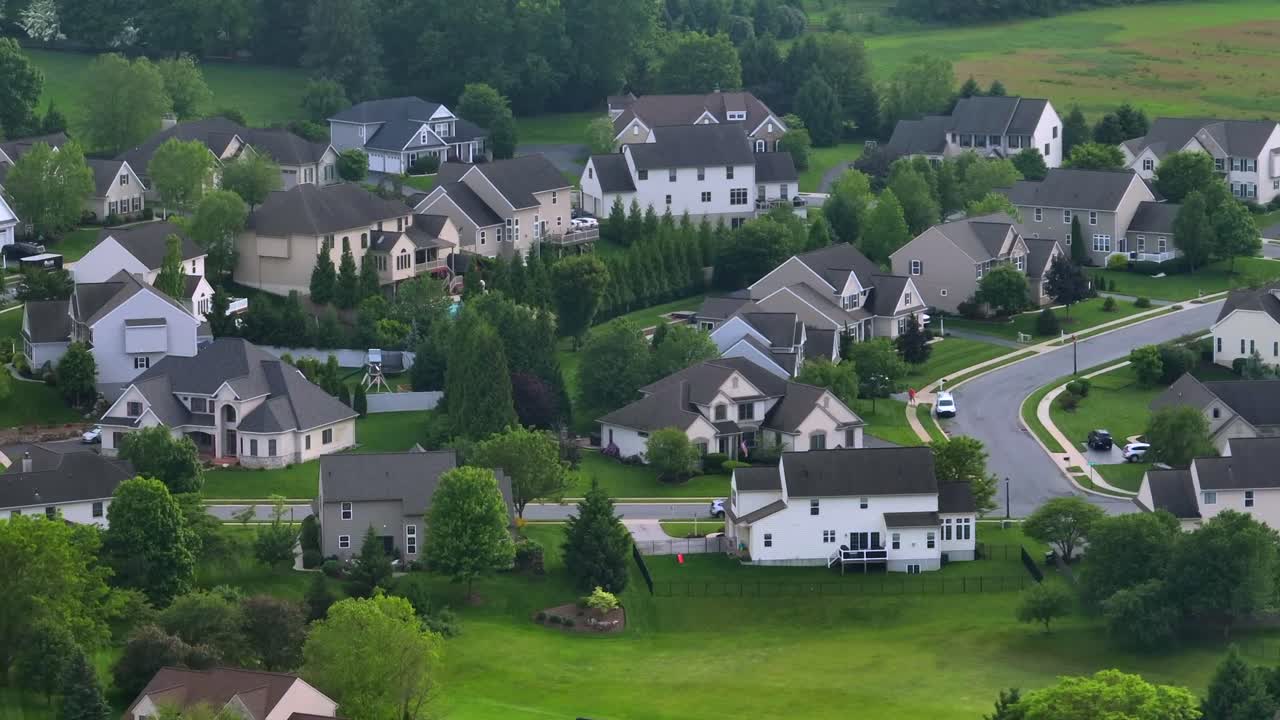 Large villas and mansion in quiet suburb district of american town. Green grass in garden of small village in United States. Foggy spring day in America. Aerial wide shot.