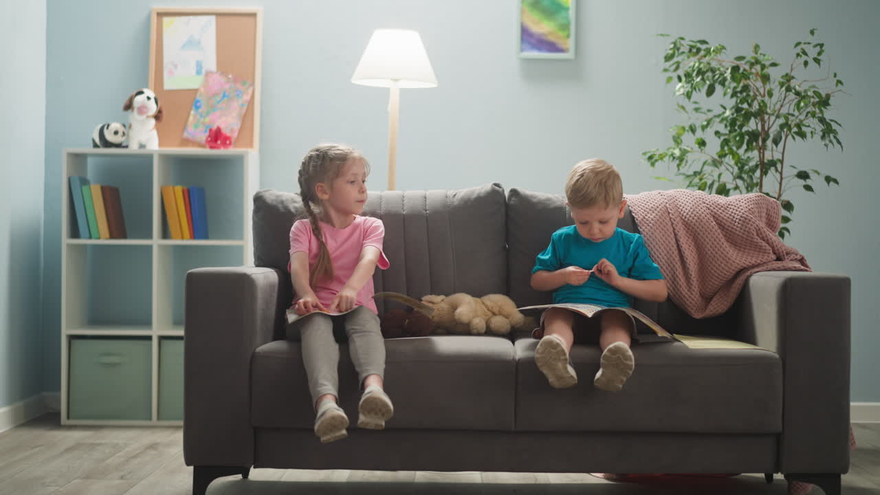 los niños están en la habitación sentados en el sofá, estudian de forma independiente