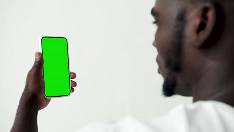 young person touch screen smartphone with green chroma key close-up. guy tapping gesture on cell phone mock-up. concept watch and show internet social media, calls, read news, app, iot, e-shopping 4k