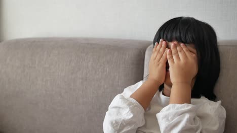 a child covering their face on a couch