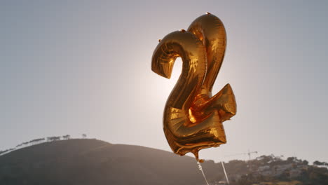 fiesta de cumpleaños globos dorados flotando en el techo soleado al atardecer número 22