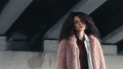 stylish girl standing alone under concrete urban bridge