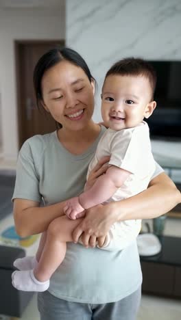 happy asian mother with her little boy in her arms at home.