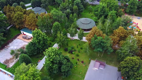 neat territory of the city park with paths and pavilions. people standing around the oval pond with fountains. aerial view.