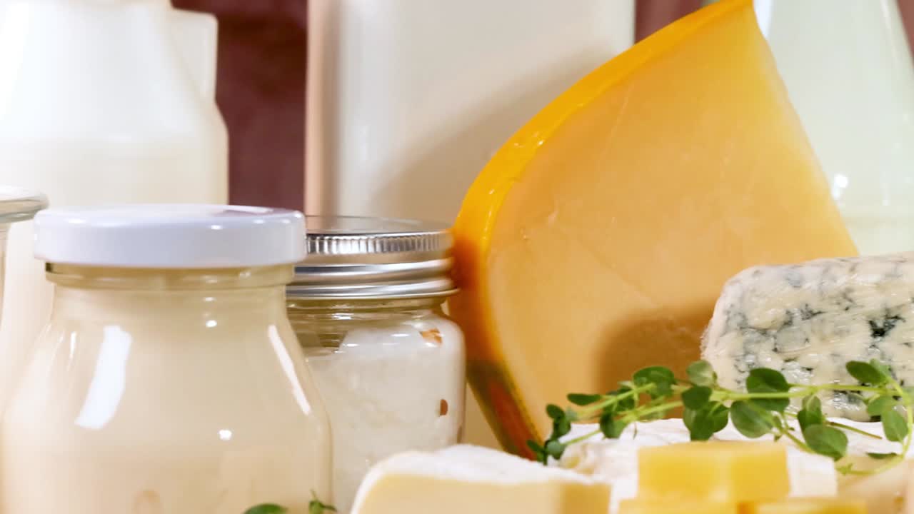 Close-up of assorted cheeses and dairy products in jars on a wooden surface.
