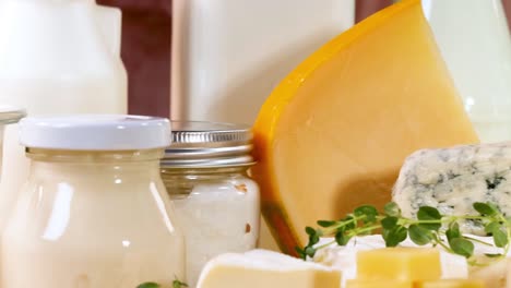 close-up of assorted cheeses and dairy products in jars on a wooden surface.