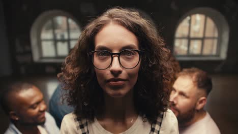 Portrait-of-a-brunette-girl-with-curly-hair-in-glasses-who-looks-at-the-camera-and-then-falls-into-the-arms-of-her-friends-during-group-therapy-and-trust-practice