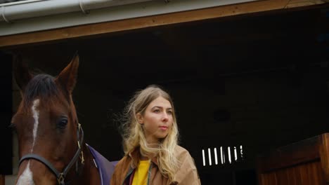 woman standing with horse in stable 4k