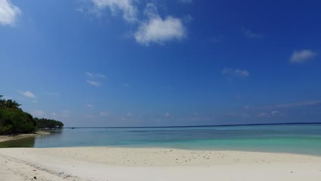 Quite-bay-with-white-sandy-beach-washed-by-calm-sea-water-under-big-clear-blue-sky-with-few-clouds-hanging-over-coastline-in-Malaysia