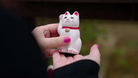 person holding a maneki-neko lucky cat figurine
