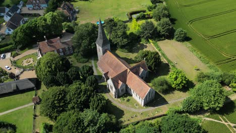 an aerial tilt shot of st john the evangelist church, with the village of ickham in the background