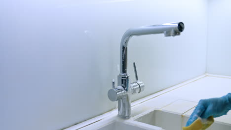 shiny faucet in bright light. a modern chrome kitchen faucet is installed above a white sink with delicate reflections capturing nearby light