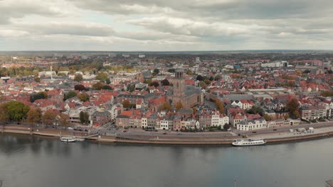 aerial drone shot closing in on the dutch medieval city of deventer from the other side of the river ijssel on a cloudy day