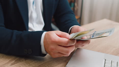 closeup of hands of businessman counting money cash use laptop earning profit success contract