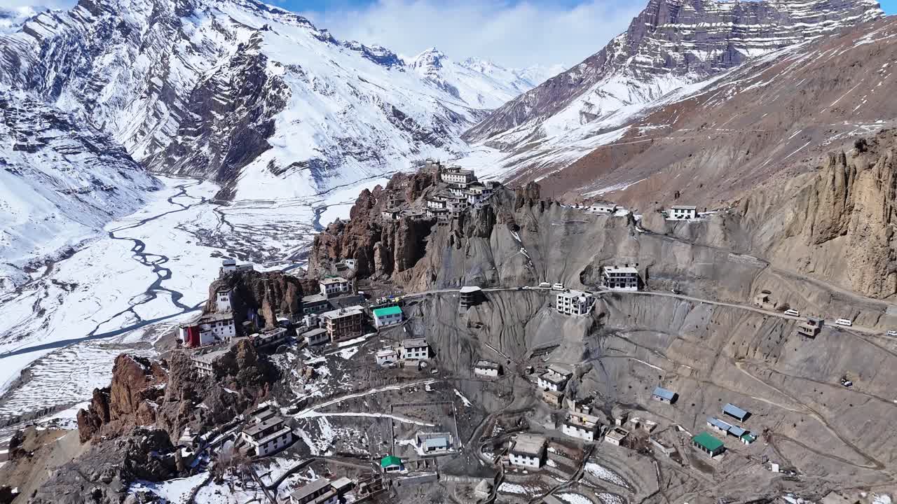 Aerial view of a Himalayan Monastery nestled in a valley with snow covered mountains