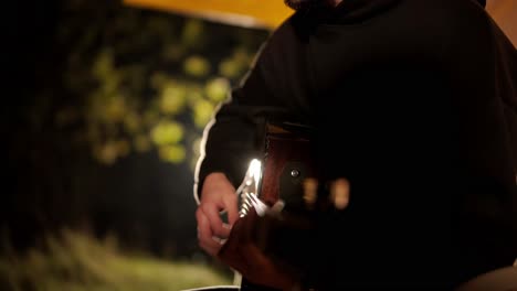 man plays the guitar and sings songs in a tent with light bulbs