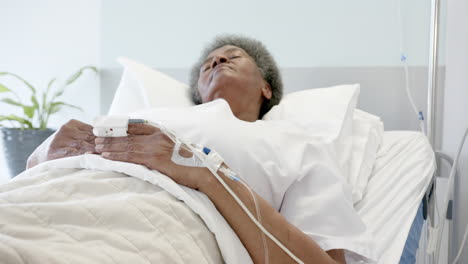 african american senior female patient sleeping in bed in hospital room, slow motion