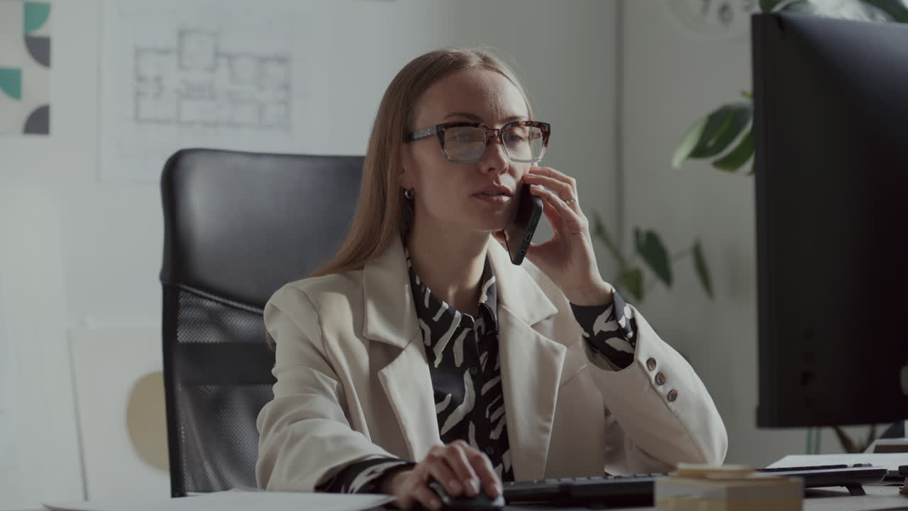Female Architect Working on Computer and Talking on Phone in Office
