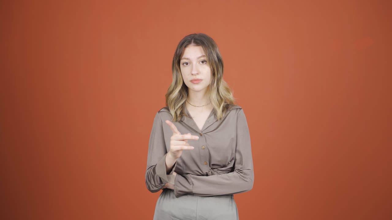 젊은 여성은 카메라를 쳐다보며 경고하고 있습니다.