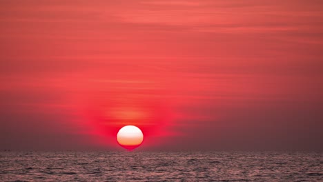 timelapse b-roll de la puesta de sol en el mar. el brillo de la luz del sol roció el color rojo sobre el cielo. el reflejo del sol y cambiar el color del agua a un tono rojo caliente. imagen dramática del paisaje del cielo del sol.