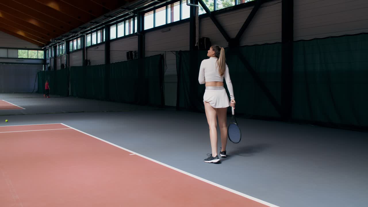 Kvinne som spiller tennis på en innendørsbane