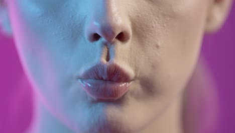 close up of woman's face and mouth, eating green grape against purple background, studio shot