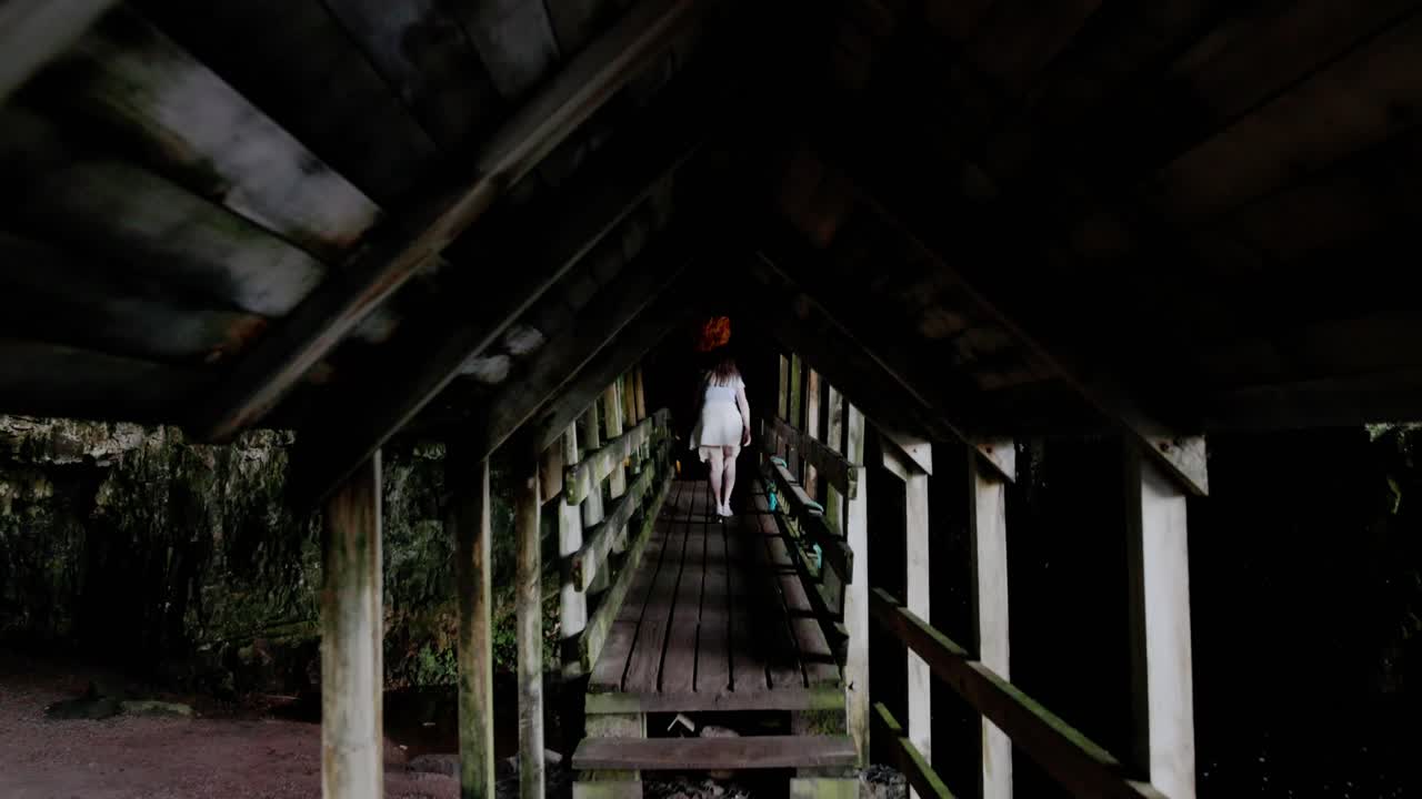 female tourist walking through a walkway to see the waterfall at Smoo Cave