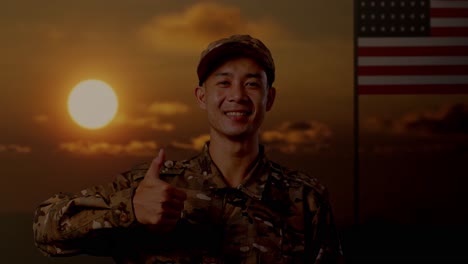 close up of asian man soldier smiling and showing thumbs up gesture while standing with flag of the united states, sunset time