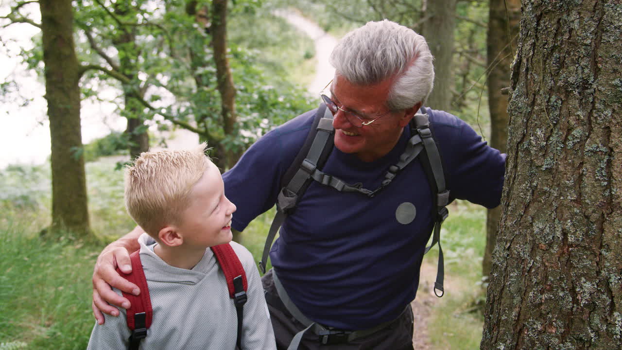 Grandfather and grandson taking a break while hiking in a forest, Lake District, UK