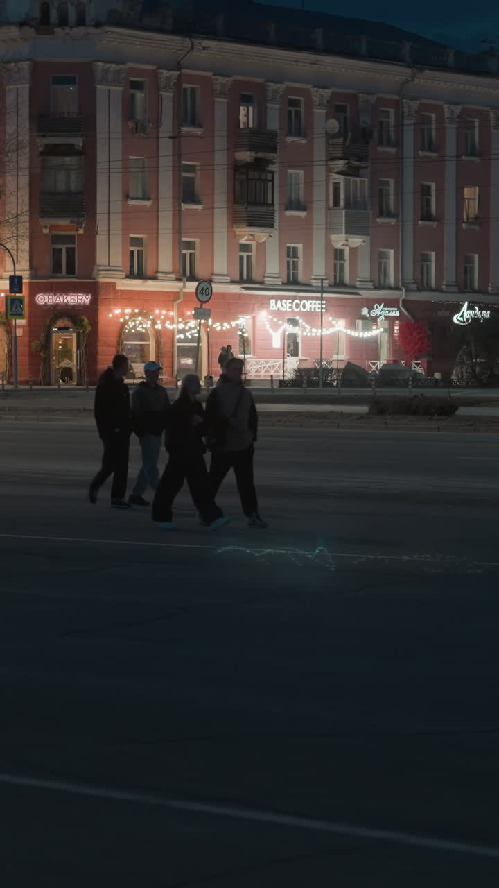 una escena nocturna de la ciudad con edificios iluminados y tiendas con luces decorativas el poste está cruzando la calle mientras los coches pasan